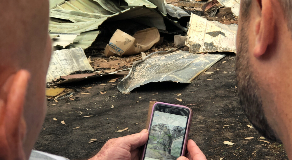 Two men inspecting the aftermath of a bushfire